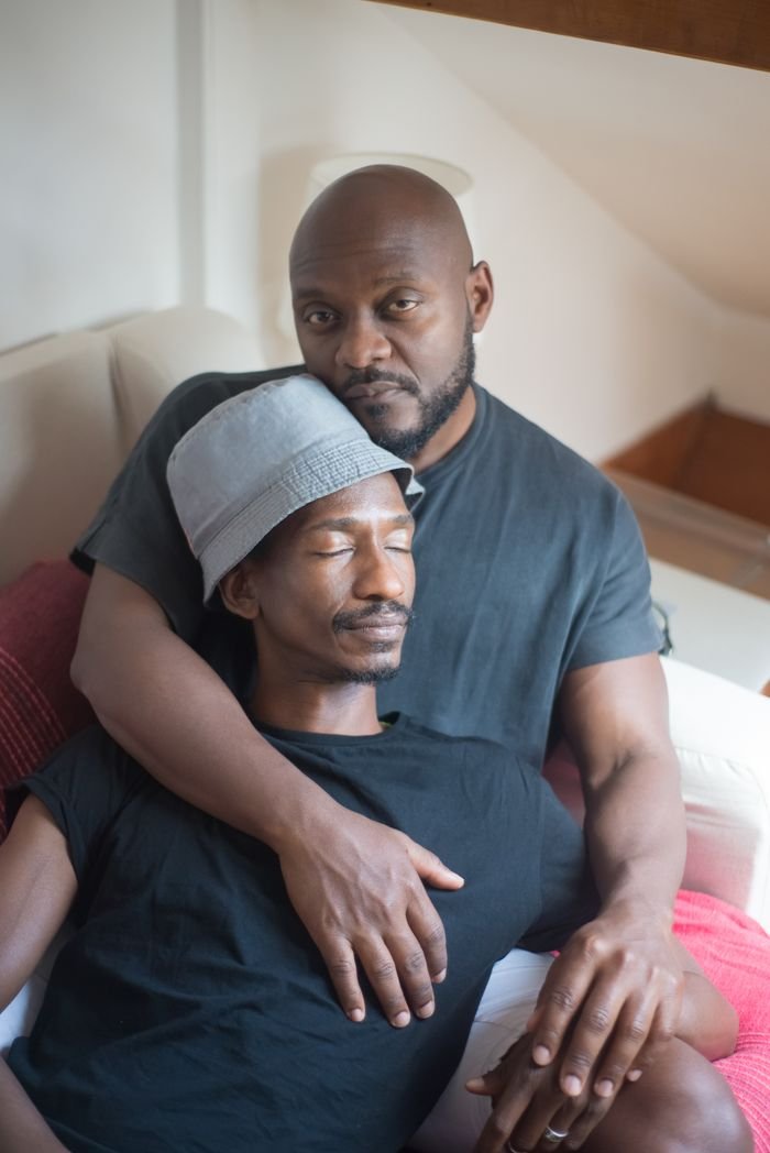 Two African American men embracing on a couch, exuding a warm and relaxed home environment.